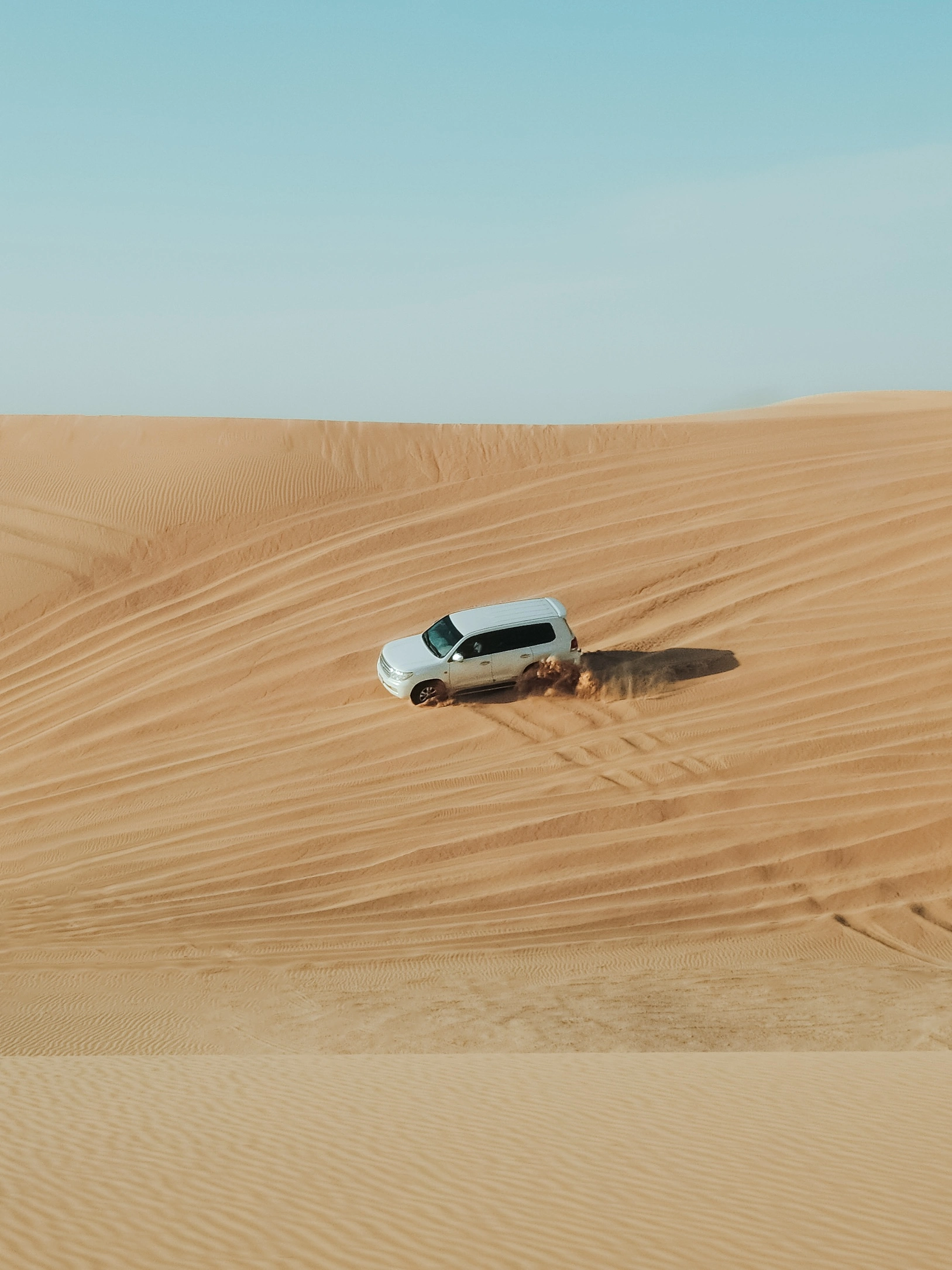 a land cruiser 4x4 drifting down a sand dune in the desert